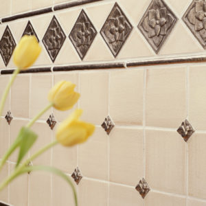 Foundry Art Carved Half-Round liner, Lotus 3-inch, and Dove metal accent inset tile off-white ceramic tile backsplash