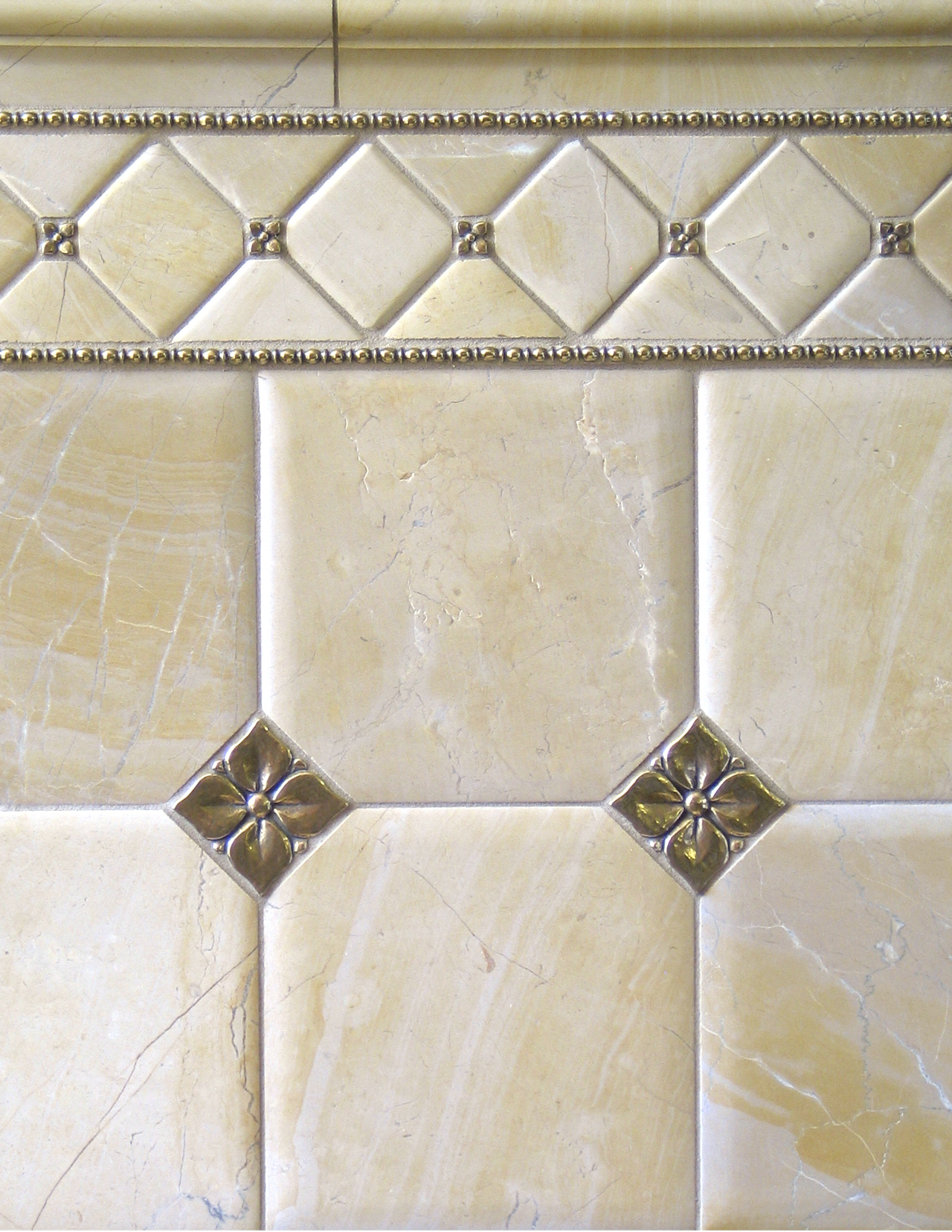 Metal accent tiles and liners: Blooming Leaf and Roman Liner in Traditional Bronze with pillowed limestone