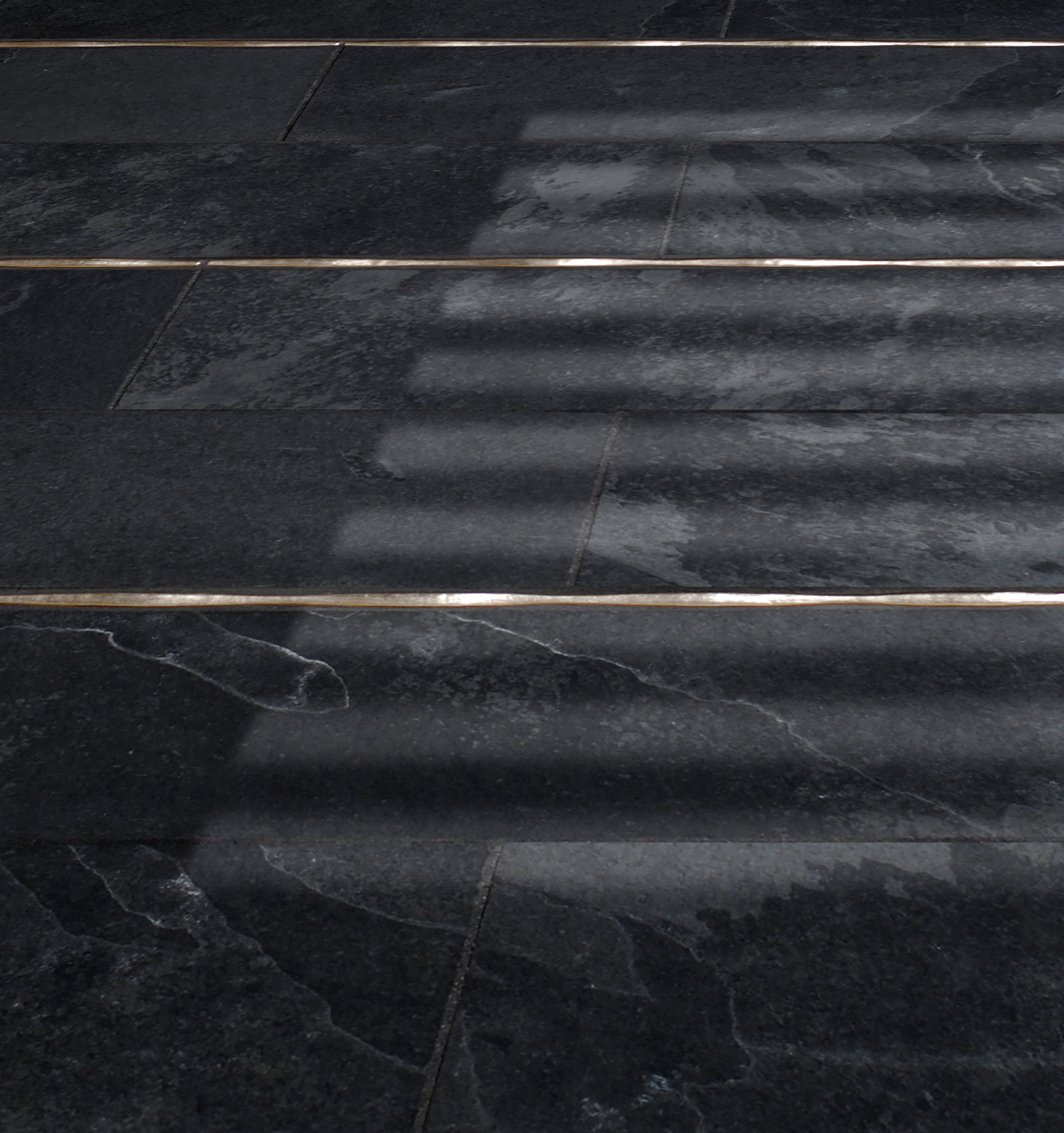 Metal accent liners: Flowing Liner in Traditonal Bronze in a dark stone floor